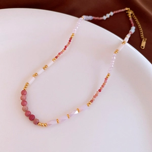 Detailed close-up of handmade beaded necklace with pink stones and gold-plated chain