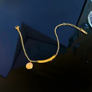Dettaglio di un bracciale in acciaio al titanio dorato con ciondolo sorriso e barra incisa