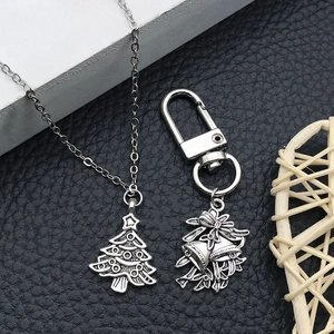 Detail of silver Christmas tree pendant and bow bell charms on textured background
