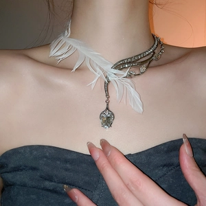 Détail d'un collier choker asymétrique avec plumes blanches et strass étincelants