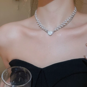 Close-up of elegant multi-layer pearl necklace featuring a sparkling diamond heart pendant