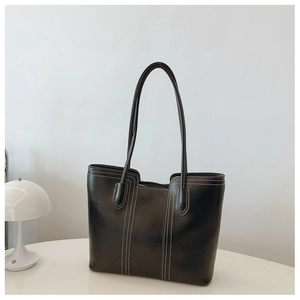 Detail of black leather tote bag featuring contrast white stitching and long shoulder straps