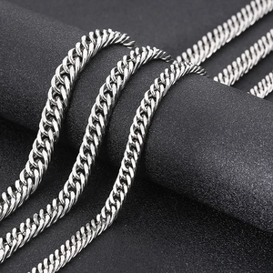 Macro shot of silver hip-hop curb chain links on a black textured background