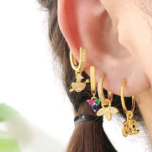 Detail of gold-plated hoop earrings featuring elephant, heart, and butterfly charms