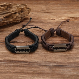 Detail of vintage braided leather bracelets with metal cross blade charms on wood