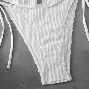 Close-up of white bikini bottoms with textured ruffles and delicate side tie strings