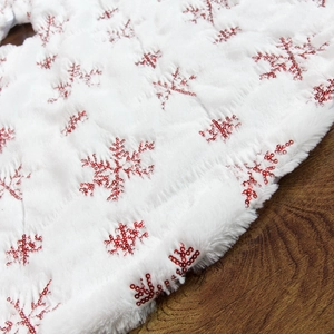 White plush Christmas tree skirt featuring red sequin snowflakes on soft faux fur
