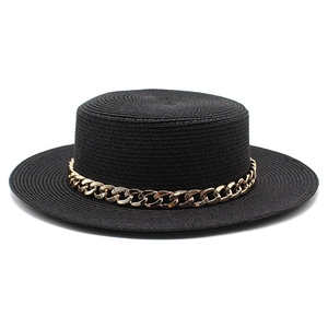 Detailed view of black straw boater hat with a chunky gold chain strap on white backdrop