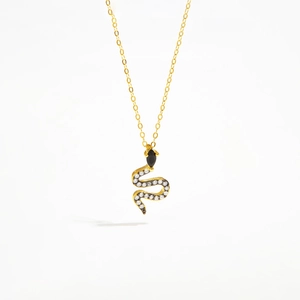 Detail of gold snake pendant with white sparkling crystals and black marquise eyes