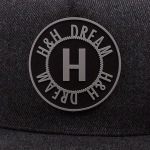Détail d'une casquette en sergé gris anthracite avec badge en caoutchouc H et H DREAM