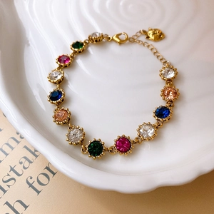 Macro detail of vintage gold bracelet with multi-colored gemstones in white ceramic tray
