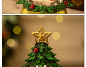 Close-up of a Christmas tree snow globe with a gold star and festive red berries