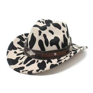 Detailed view of thick cow print cowboy hat with brown leather band and metal studs