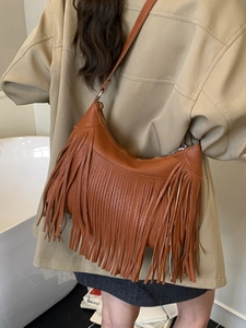 Deep brown tassel shoulder bag with long fringe and minimalist curved leather design