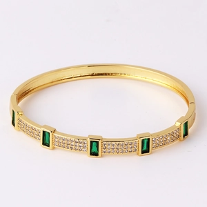 Detailed close-up of gold plated bracelet with green rectangle stones and micro white zircons