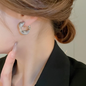 Close-up of minimalist silver twisted hoop earrings with fine grid texture on model