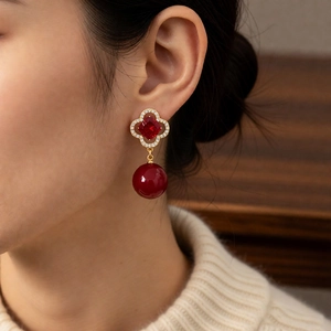 Close-up of vintage flower earrings with red stones and pearls on a female model