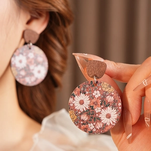 Close-up of vintage wooden round earrings with painted floral patterns for women
