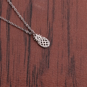 Macro shot of silver hollow pineapple pendant necklace on brown textured surface
