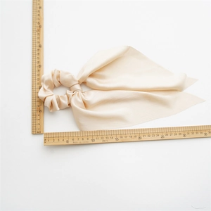 Detailed view of beige satin ponytail scrunchie with long ribbons and measuring rulers