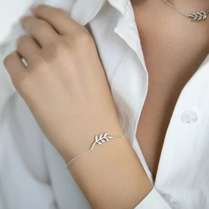 Detail of minimalist 925 sterling silver olive leaf bracelet and necklace on model
