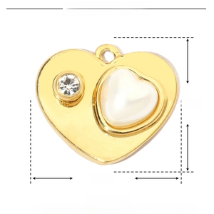Macro detail of gold heart pendant featuring a pearl, rhinestones, and size measurements