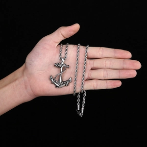 Close-up of punk style skull anchor pendant in silver finish on a twisted chain