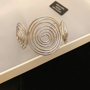 Macro detail of silver S925 sterling silver open bangle with spiral disk texture