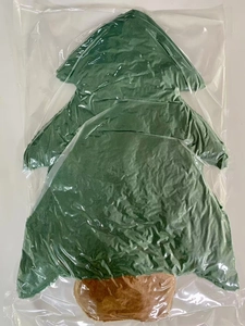 Detail view of a plush green Christmas tree shaped pillow in clear plastic packaging