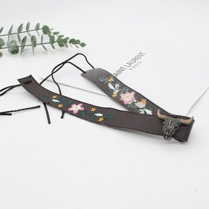 Close-up of bohemian embroidered leather hat bands with floral patterns and a bull skull charm