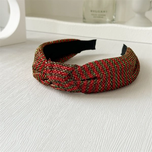 Detail of red and green striped fabric headband with a stylish knot on a white surface