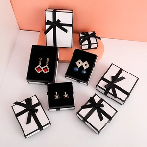 Detailed view of square and rectangular white jewelry boxes with elegant black ribbons