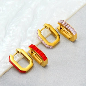 Macro detail of U-shaped gold plated titanium steel earrings with ruby and pink zircon inlay