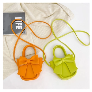 Detail view of mini PU leather crossbody bags with large bow in orange and lime green colors
