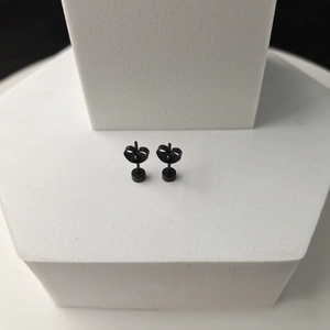 Macro shot of black stainless steel round stud earrings with butterfly backs detailing