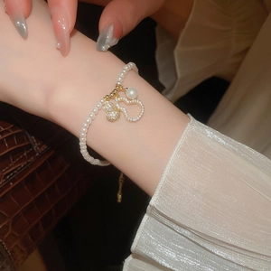 Détail macro d'un bracelet de perles avec pendentifs gourde dorés et zircons sertis