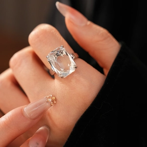 Close-up of a silver ring with a large emerald-cut rectangular zircon on a woman's finger