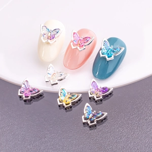 Detail showing 3D aurora butterfly nail charms with iridescent wings on metal base