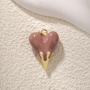 Detail of a dusty rose heart pendant with golden lava drip effect on white texture