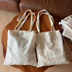 Detailed embroidery texture on vintage beige lace tote bags displayed on a wooden table