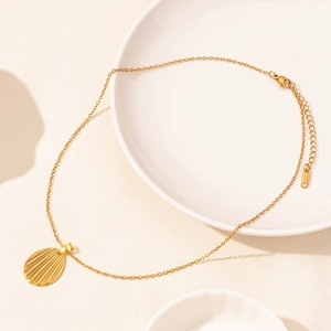 Close-up of golden shell pendant necklace with cross chain and lobster clasp