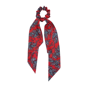Detail of red silk ponytail scrunchie with blue and white paisley print on white background