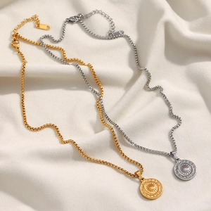 Detail of gold and silver sun pendant necklaces on white fabric, box chain style