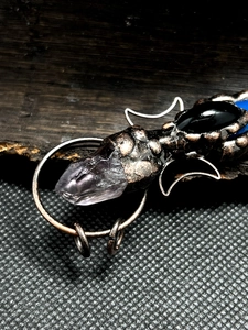 Detail of vintage bronze moon pendant with purple crystal and black agate stone