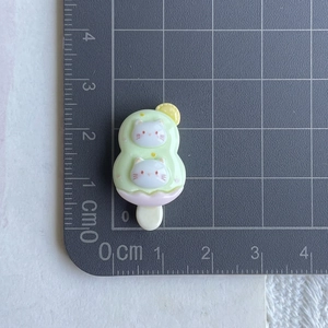 Detail of a 2.5cm green resin popsicle charm with cat icons and lemon slices