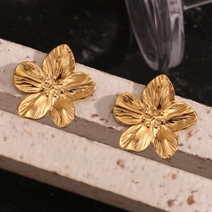 Macro shot of 18K gold plated brushed petal earrings on a textured stone base