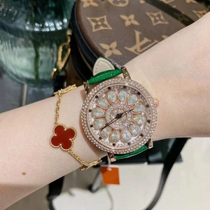 Close-up of luxury women's watch with rotating diamond flower dial and green leather strap