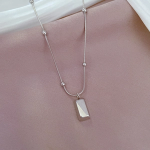 Detailed shot of titanium steel snake chain necklace with beads on soft silk fabric