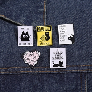 Détails de cinq pin's chat en émail sur denim avec des slogans humoristiques