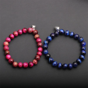 Bracciali magnetici di coppia in occhio di tigre con cuori su sfondo scuro testurizzato